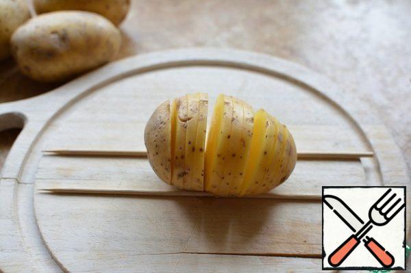 Potatoes clean cut into circles, without cutting to the edge, using skewers placed under it;