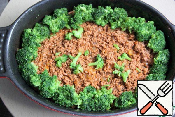 Grease the baking dish with vegetable oil and put 2/3 layers of minced meat. On the sides are broccoli inflorescences.