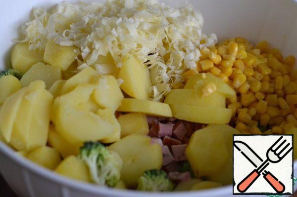 In a large bowl, mix chopped potatoes, broccoli, ham, corn and half hard cheese.