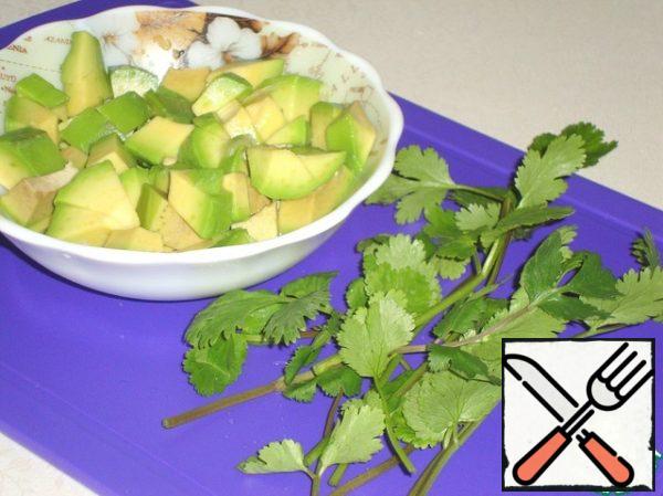 Clean the avocado, remove the bone, cut into cubes and sprinkle with lemon juice from darkening.
Cut a few branches of cilantro or any other greens.