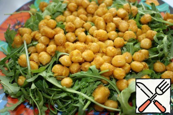 Place the arugula on a platter, then the roasted and slightly cooled chickpeas.
