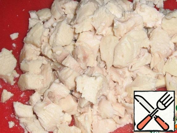 Boil chicken fillet and cut into large cubes or disassemble into fibers.