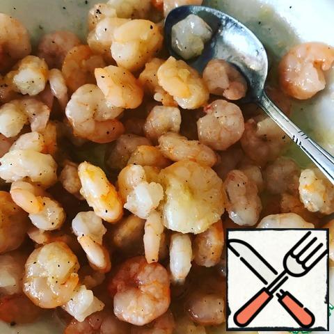 Shrimp boil a couple of minutes, put in a plate. Prepare the dressing: squeeze out a slice of garlic, pour 2 tablespoons of olive oil, add salt and pepper. Stir and add to shrimp.