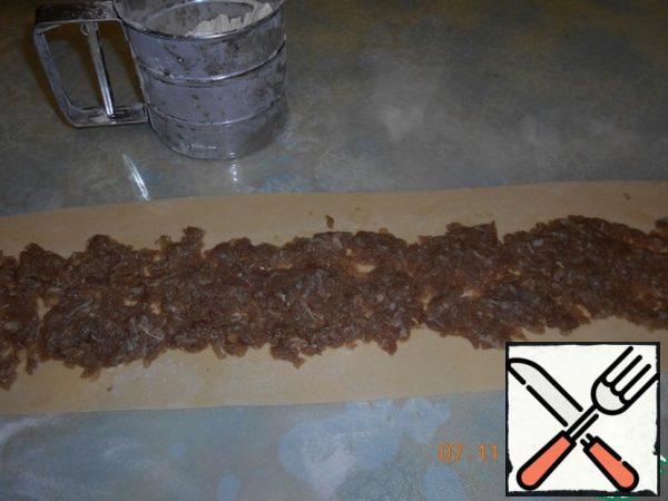 The dough is divided into 2 parts, each roll out into a tape width of 12-13 cm, lay out the minced meat, roll up.