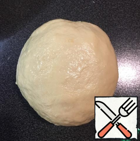 Spread the dough on the table and knead thoroughly for 7-8 minutes until the dough is smooth, soft and elastic. Roll the dough into a ball, lightly lubricate with vegetable oil.