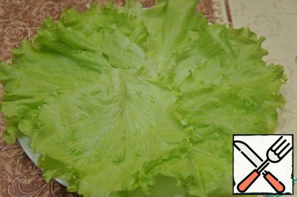 Flat dish lined with green lettuce leaves.