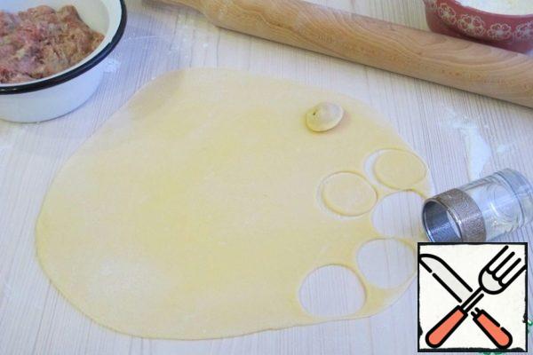 Next, separate a small piece from the dough, roll out the layer. Cut the circles with a notch, add minced meat to the middle of each circle. The edges connect.
