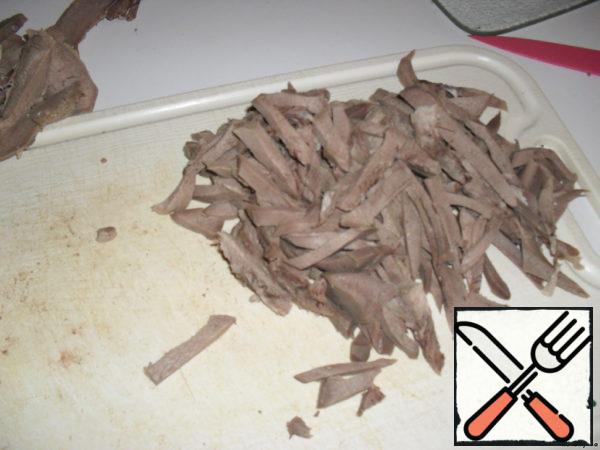 The tongue is boiled, cleaned, cooled and cut into strips.