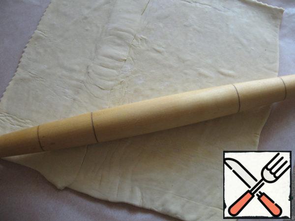Puff unleavened dough roll out on baking paper (two parts of the glue overlap).