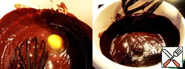 When the chocolate mass becomes less hot, beat the eggs one by one, stirring thoroughly with a whisk.

