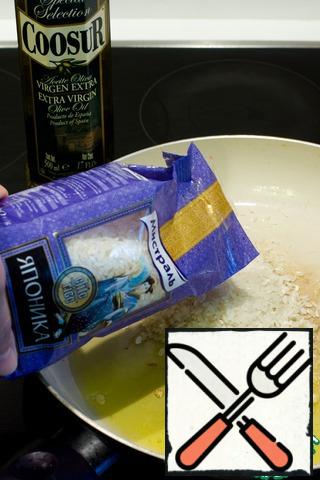 In a frying pan, heat olive oil, add the chopped garlic cloves and add the rice to the risotto. Fry the rice for a few minutes.