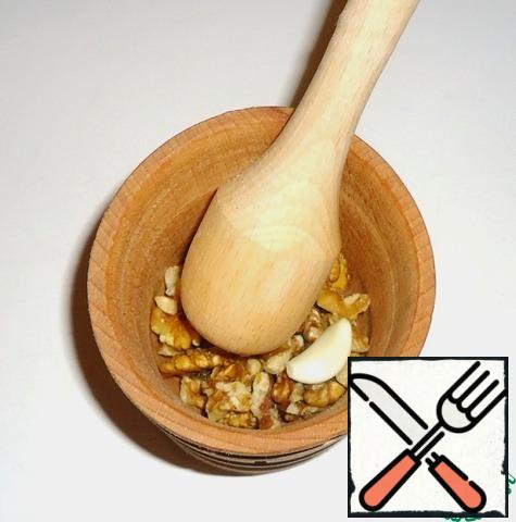 Prepare salad dressing. Grind walnuts and garlic in a mortar.