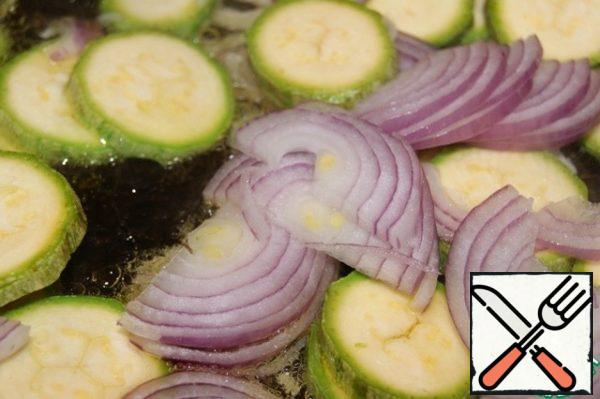 Remove the garlic. Add the onion, cut into half rings, and the zucchini cut into rings. Simmer for 2 minutes. Set aside in a separate container. The oil remaining in the pan.