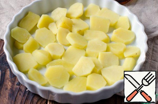 Peel and boil the potatoes, cut into slices and boil in salted water for 5-7 minutes. Put the potatoes in a heat-resistant form, greased with oil.
