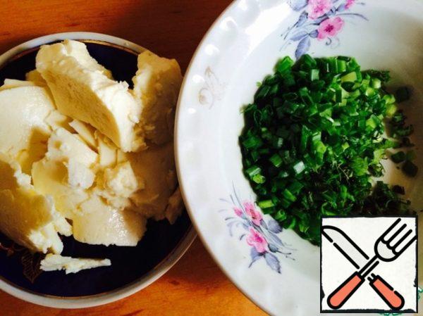 While the dough is baked, prepare the remaining filling. Cut the finely green onions, cut the cheese into pieces.