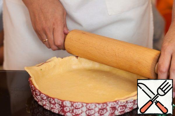 Grease the mold (20 cm) with butter, roll out the dough into a layer between two sheets of baking paper, transfer to the mold and remove the excess with a rolling pin.
