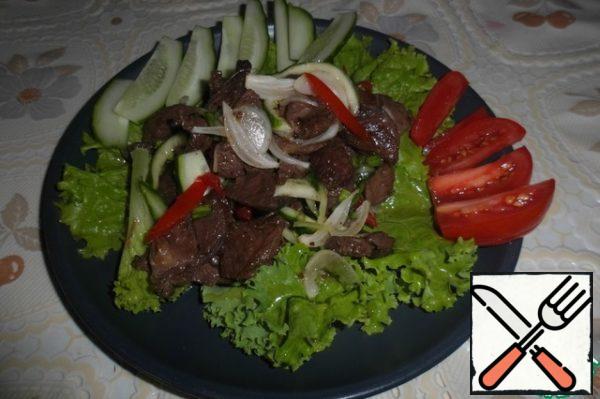 Cut the remaining tomato and half of the cucumber into slices.
Arrange the lettuce leaves on plates, put the lamb and vegetables on top, pour the sauce remaining in the bowl, garnish with slices of fresh vegetables.