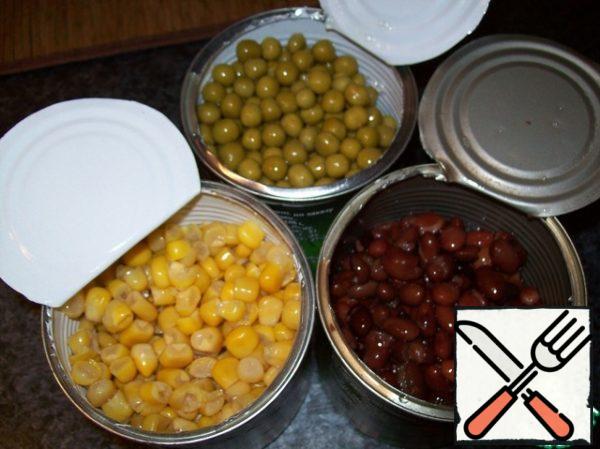 She opened cans of beans, peas and corn, drained the liquid, poured the contents into a bowl.
