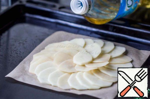 Potatoes peel and cut into thin slices. On a baking sheet spread a square of parchment. Put the potato petals overlap in a circle. Grease with vegetable oil and salt. Cover with another square of parchment. On top put another baking sheet or form to potato gratin remained flat. Put on 10-15 minutes to bake at 180 C.