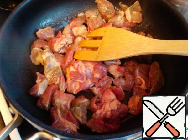 Heat the oil in a frying pan, throw the sliced meat into it and fry on the biggest fire, so that each piece is covered with a crust.