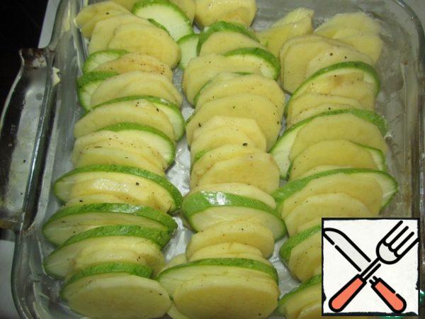 Peel the potatoes, cut the potatoes and zucchini into 0.5 cm thick circles, season with salt and pepper, add nutmeg, chopped garlic without a central stick, lubricate the refractory mold with butter and lay out the "packages" of potatoes and zucchini (see photo)
