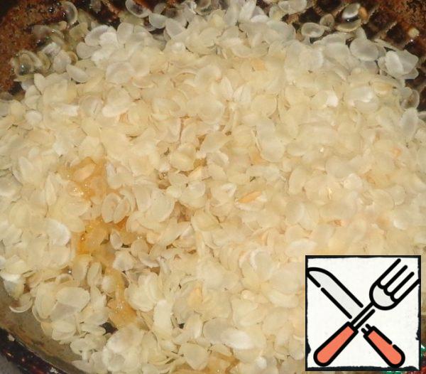 Add the rice flakes to the onion and mix well.
