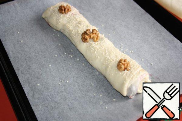 Carefully shift the strudel on a baking sheet. Decorate with halves of nuts and sesame seeds.