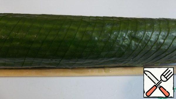Put the cucumber on a board, sticks should turn out on the sides of the cucumber, cut the cucumber at an angle of 45 degrees so that the cut end does not stick. Turn 180 degrees and do the same.
