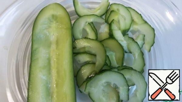The rest of the cucumber to cut into two halves, remove the middle and cut into very thin slices.
