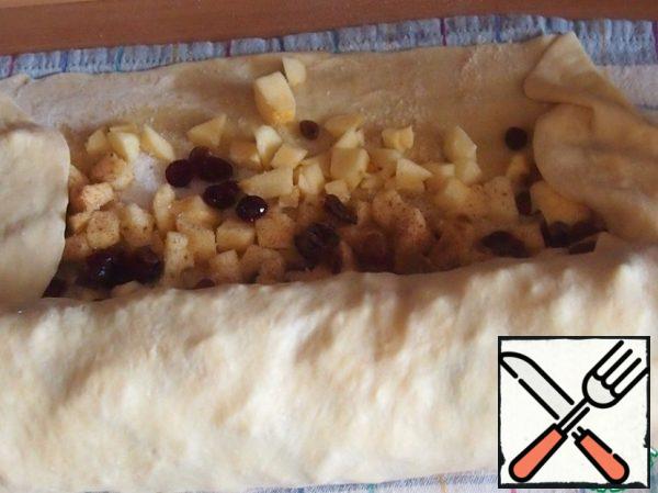 Wrap the dough around the edges and use a towel to roll up the roll. Lubricate the end of the dough with water so that it sticks better to the roll.
