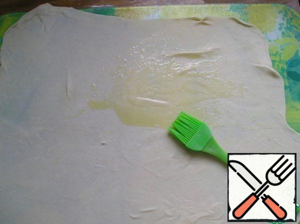 Divide the dough into 2 parts. Roll out one of them on a floured surface as thinly as possible and lubricate with a thin layer of oil. I use olive oil here, my grandmother used ghee. or melted in half with vegetables. The choice of oil depends entirely on your preferences.
