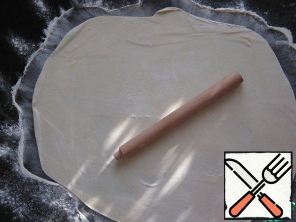 Roll the dough in flour, sprinkle the table with a thin layer of flour, roll out the dough with a rolling pin as thin as possible.