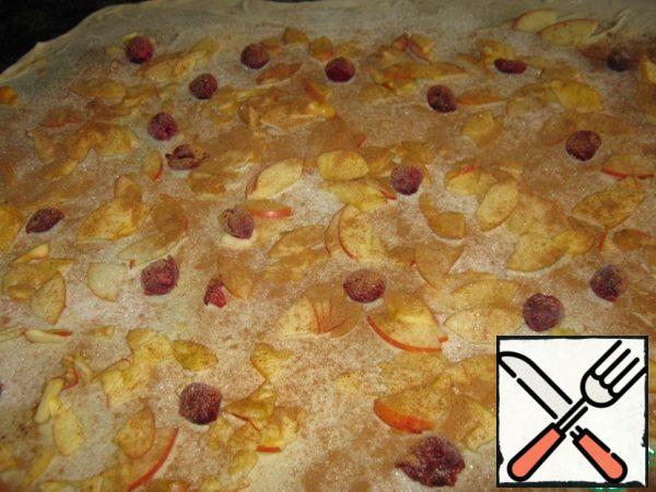 On the resulting layer of dough, apply rust with a brush. brush with oil (not a solid layer, but with strokes), sprinkle with breadcrumbs, evenly distribute apples, cherries, sprinkle with cinnamon, 4 tablespoons of sugar and vanilla.

