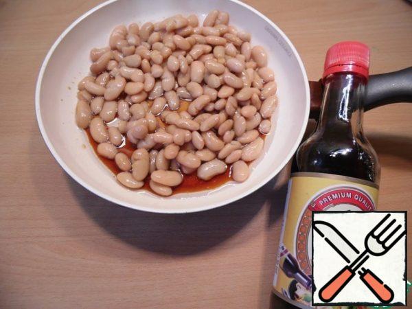 Drain the liquid from the beans, chop the garlic, put it in a frying pan greased with vegetable oil, add soy sauce and wine vinegar and simmer, stirring occasionally, until the liquid evaporates.
Cool the beans, mash them slightly.
