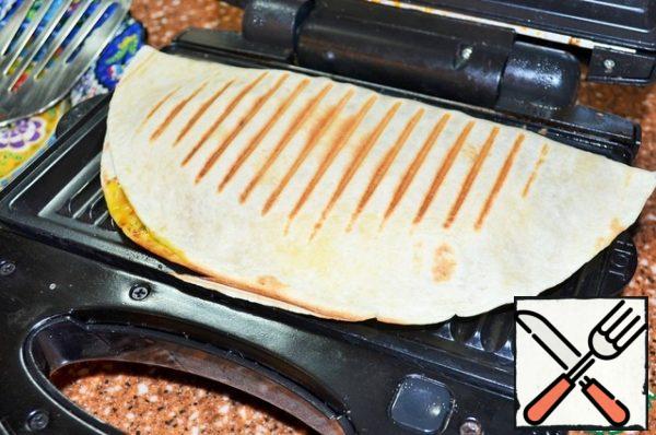 Cover with half the tortillas, heat them on the grill.
I use an electric batten with a grill nozzle.
Perhaps just fry in a dry pan, for 4 minutes each cake.