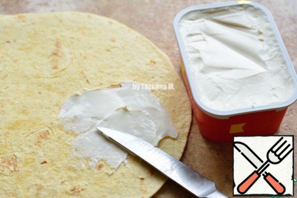 Grease the tortillas with cream cheese;