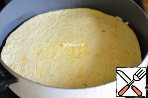 Making sure with the help of a spatula that the omelette departs well from the bottom, cover the omelette with a flat cake smeared side down and turn the pan to the surface; 