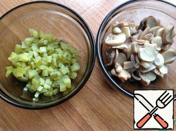 Cut the cucumbers into small cubes. Drain the excess liquid from the mushrooms. If they are large, then cut them into small pieces.

