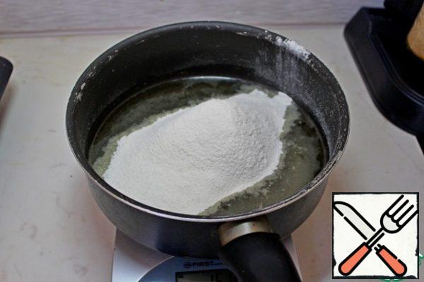Let's start by preparing the dough for profiteroles.
To do this, pour water and vegetable oil into a saucepan, bring to a boil and, without removing from the heat, add the sifted flour with constant stirring.