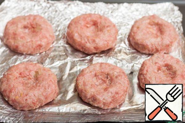 Form round cutlets from minced meat, place on a baking sheet covered with parchment, make recesses in the center
(do not use foil, do not repeat my mistakes, cutlets then very difficult to remove).
Send in the oven, preheated to 200 C for 10 minutes.