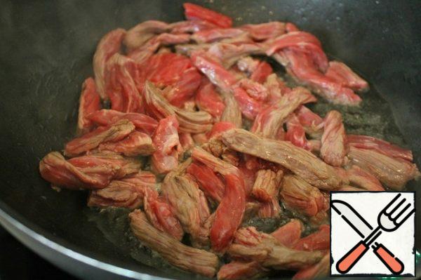 In a frying pan, heat the oil and fry the meat, stirring until tender.