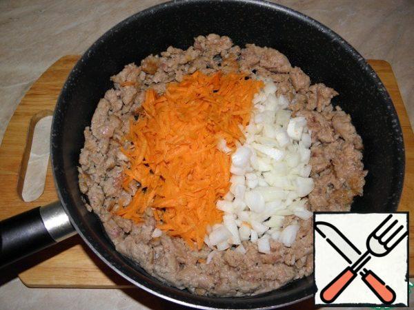 Press the minced meat against the walls of the pan and add finely chopped onions and grated carrots to the center. Lightly fry the vegetables in the center of the dish.
