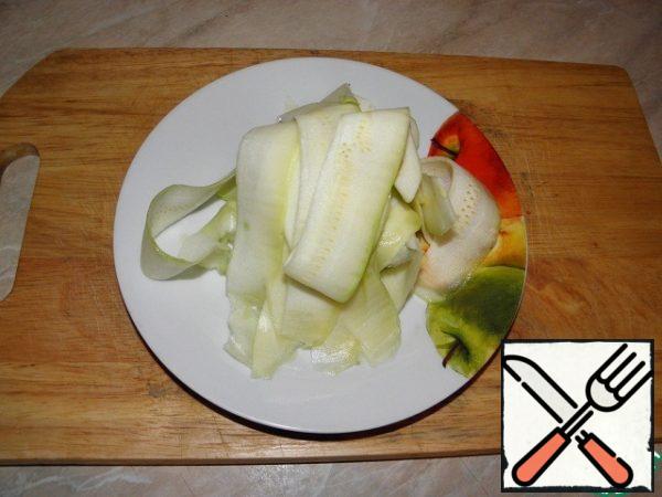 While the vegetables with minced meat are cooking in a frying pan, prepare the zucchini. Wash, dry, peel. Cut the zucchini lengthwise into two parts, remove the seeds from each with a spoon, a vegetable peeler or a knife — for whom it is more convenient, cut off the tips. At this stage, the weight of the zucchini is determined. Remove the zucchini pulp layer by layer.
