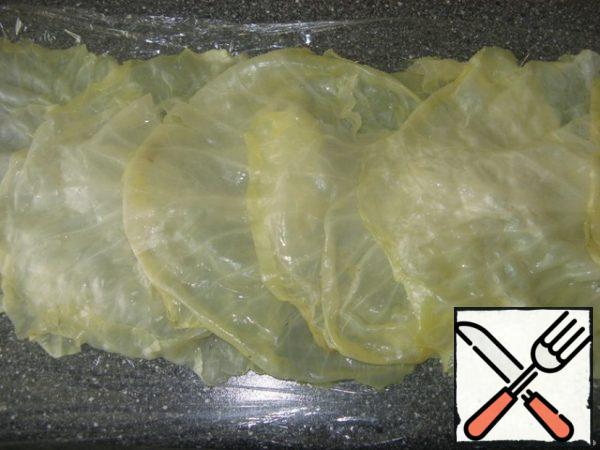 On plastic wrap spread cabbage leaves overlap.