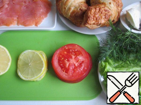 Croissants are ready, without filling.
Lightly salted fish cut into thin slices. There is a ready-to-store slice.
Cut the tomato into thin slices.
Wash and dry the lettuce leaves and dill. If desired, you can take other greens.
Wash the lemon (you can pour boiling water over it), cut in half. We'll need half a lemon. Cut 4 thin slices from it, squeeze the juice from the rest and sprinkle the fish with it.