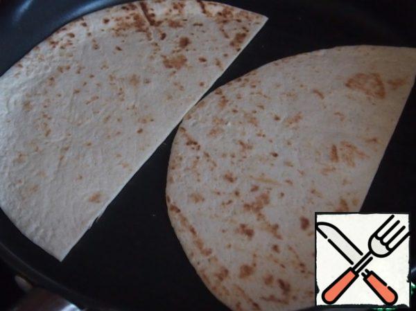 When the meat is ready, prepare a tortilla. Cut it into two halves and put it in a hot, dry frying pan. For a beautiful picture, it's better to use a grill pan, but it doesn't matter. Heat the cake on both sides for just a few seconds so that it becomes warm and elastic. The main thing is that the tortilla does not dry out.
