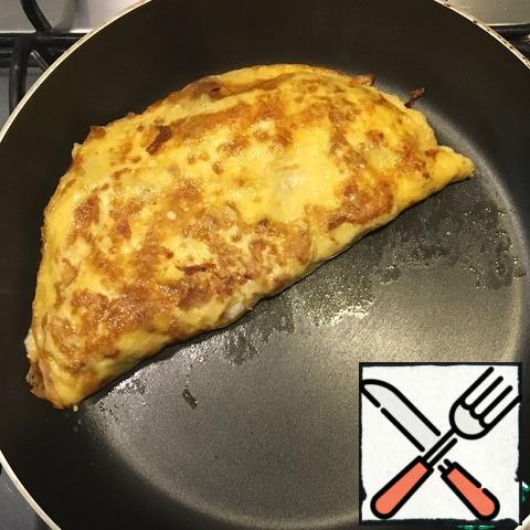 Carefully, using a spatula turn the omelet in half, fry on both sides for 1-2 minutes.