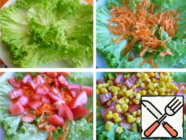 Wash the lettuce leaves, dry them, sort them out with your hands.
Put lettuce leaves on a plate.
Grate the carrots on a coarse grater.
Cut the tomato into cubes, put it on top of the carrots.
Add the corn.