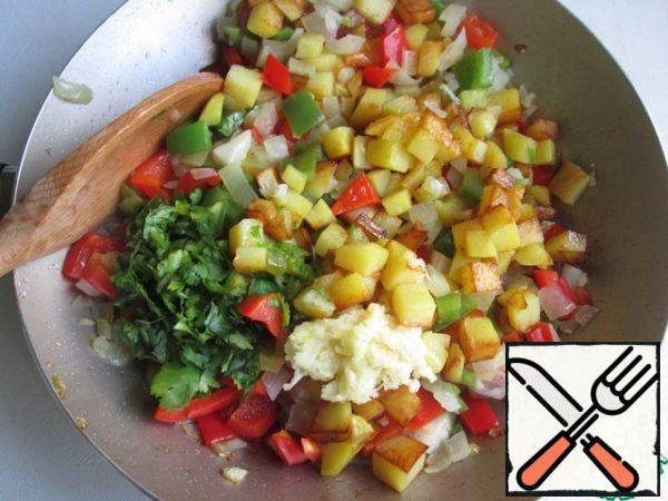Then add the fried potatoes, finely chopped coriander and chopped garlic. Mix it.
