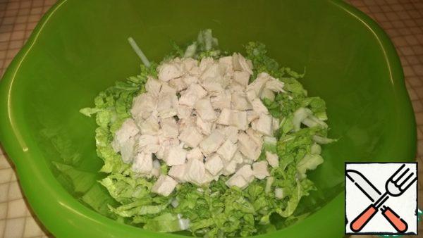 Thinly slice the Peking cabbage. Pour into a bowl. Cut the boiled chicken fillet into cubes and send it to the Peking cabbage.

